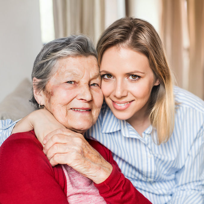 Portrait of an elderly grandmother with an adult granddaughter sitting on the sofa at home.